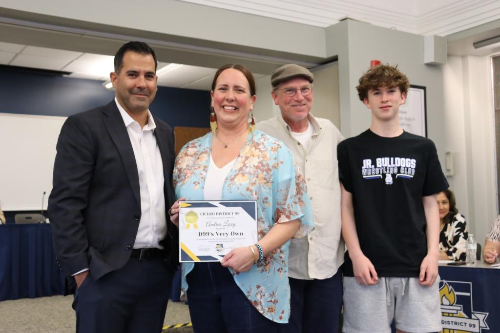 Four people stand together, smiling, with a certificate being held.
