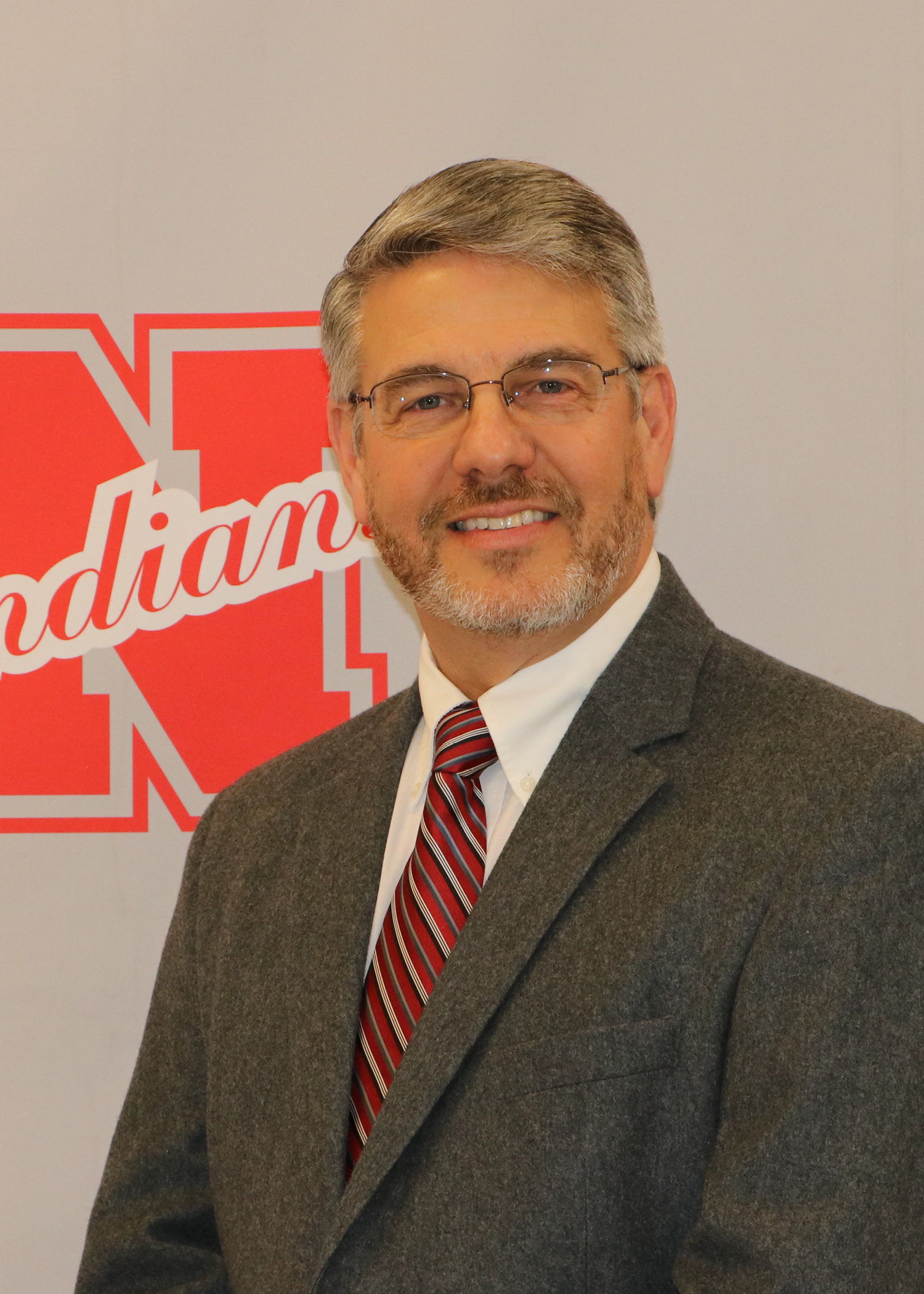 A man in a suit and tie smiles at the camera.