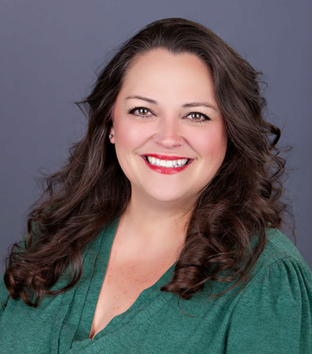 A woman with long brown hair smiles at the camera.