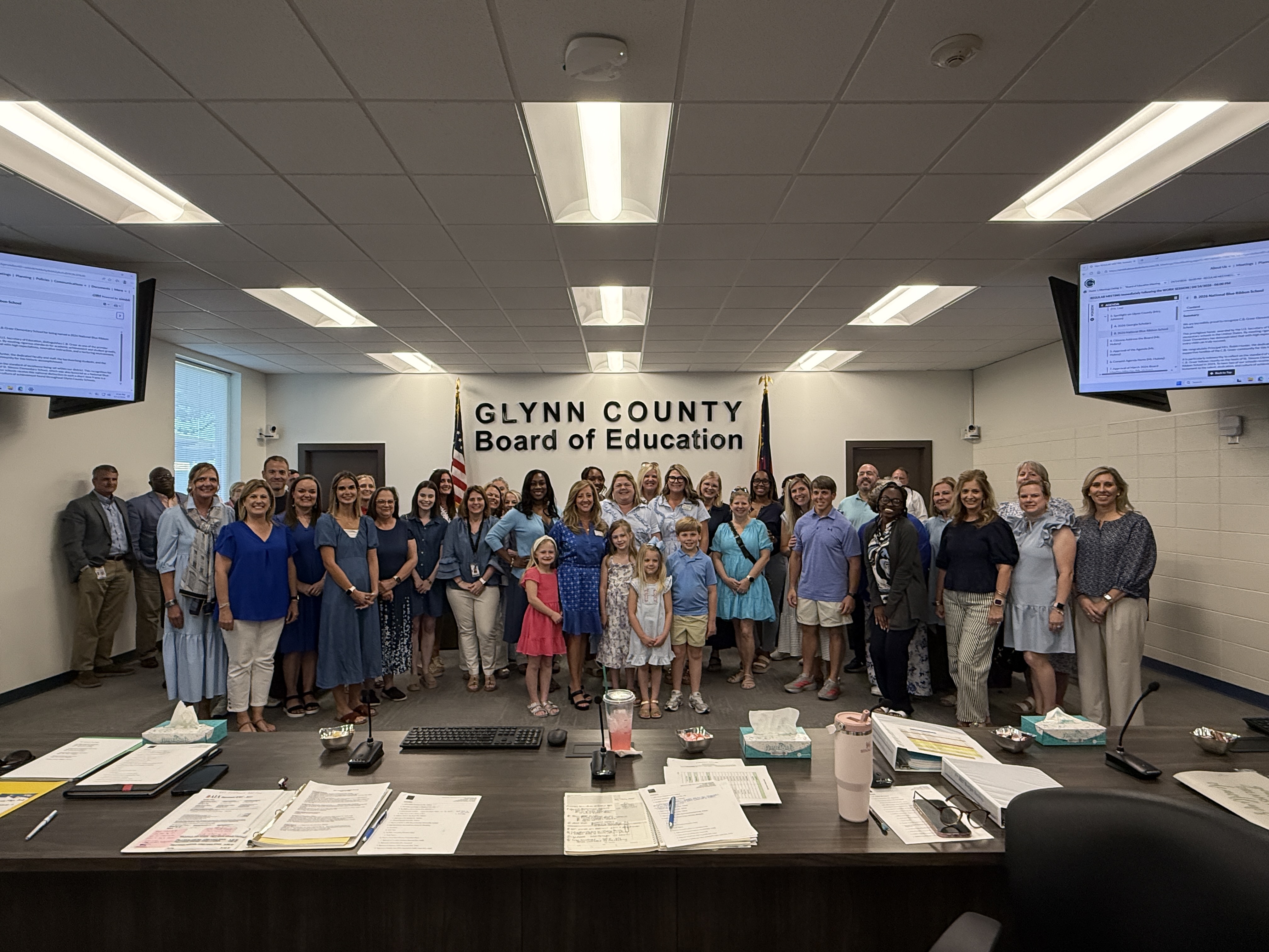 A large group of people pose for a photo in a meeting room.