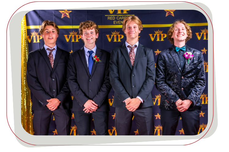 Four young men in suits pose in front of a VIP backdrop.
