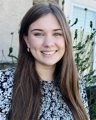 A young woman with long brown hair smiles directly at the camera.