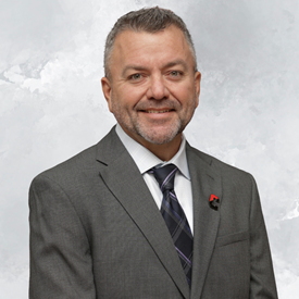 A man with short gray hair and a beard smiles at the camera.