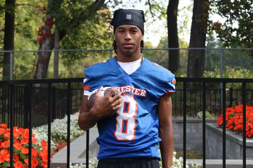 A young man in a blue football jersey holds a football, posing for a photo.