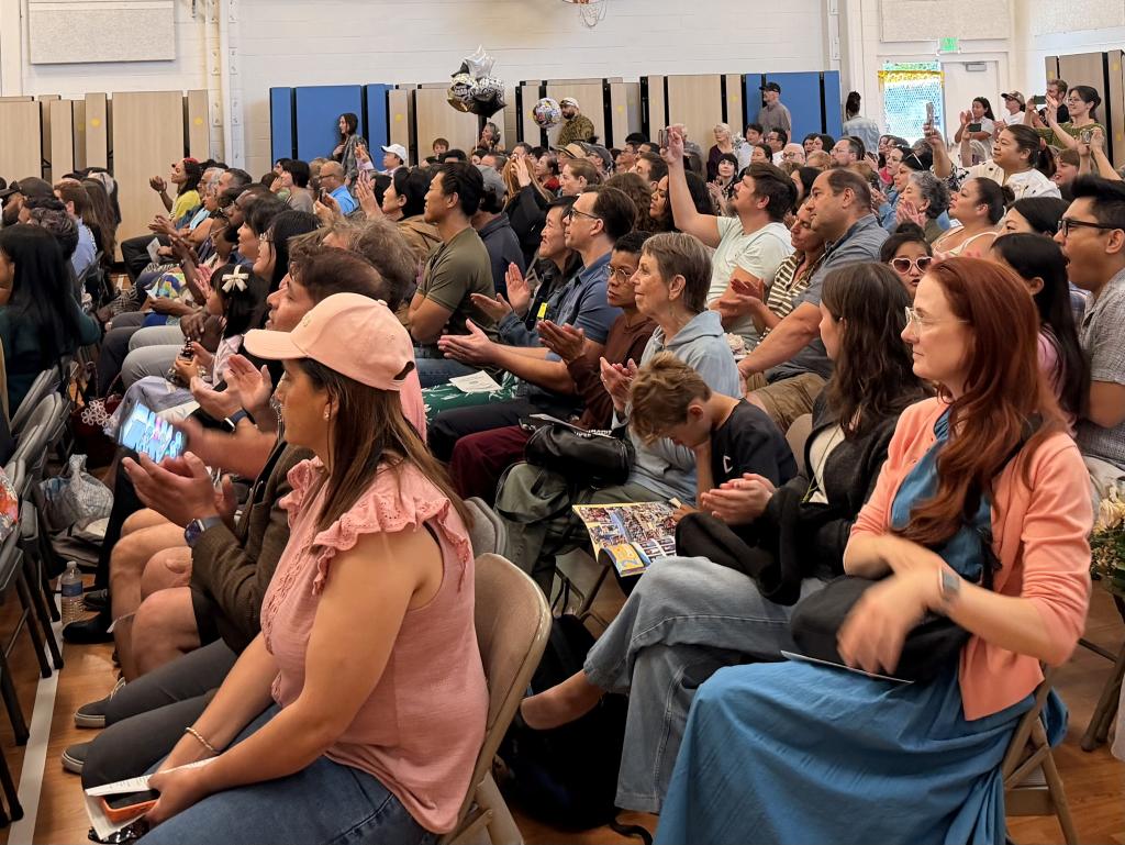 A diverse group of people are seated in a room, attentively listening.