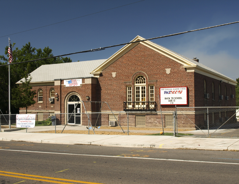 A brick building with a white roof and arched windows sits on a sunny day.