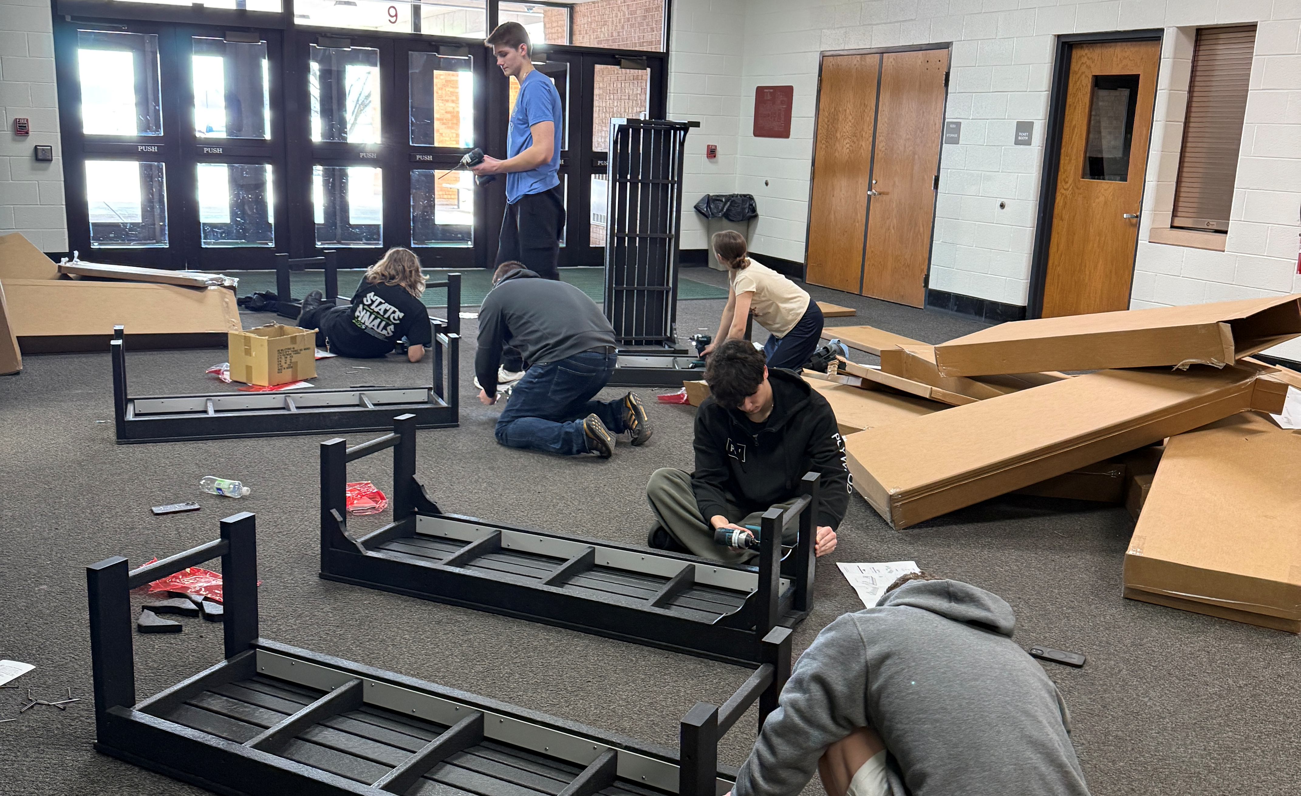 A group of people assemble furniture in a well-lit room.