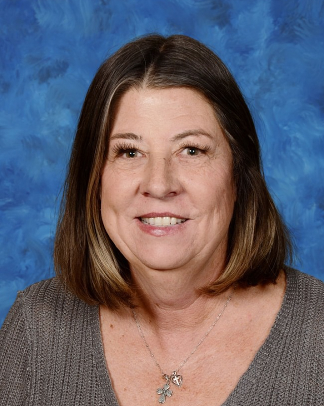 A woman with shoulder-length brown hair smiles at the camera.