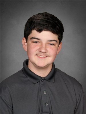 A young person with dark hair smiles at the camera, wearing a gray polo shirt.