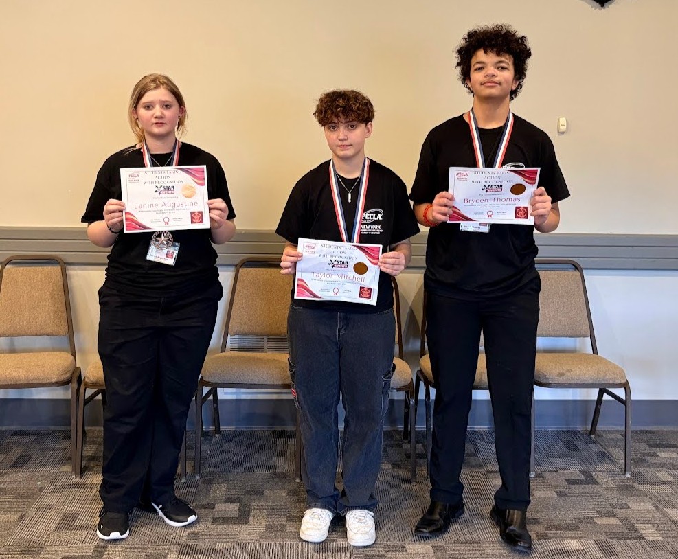 Three young people stand proudly, holding certificates and wearing lanyards.