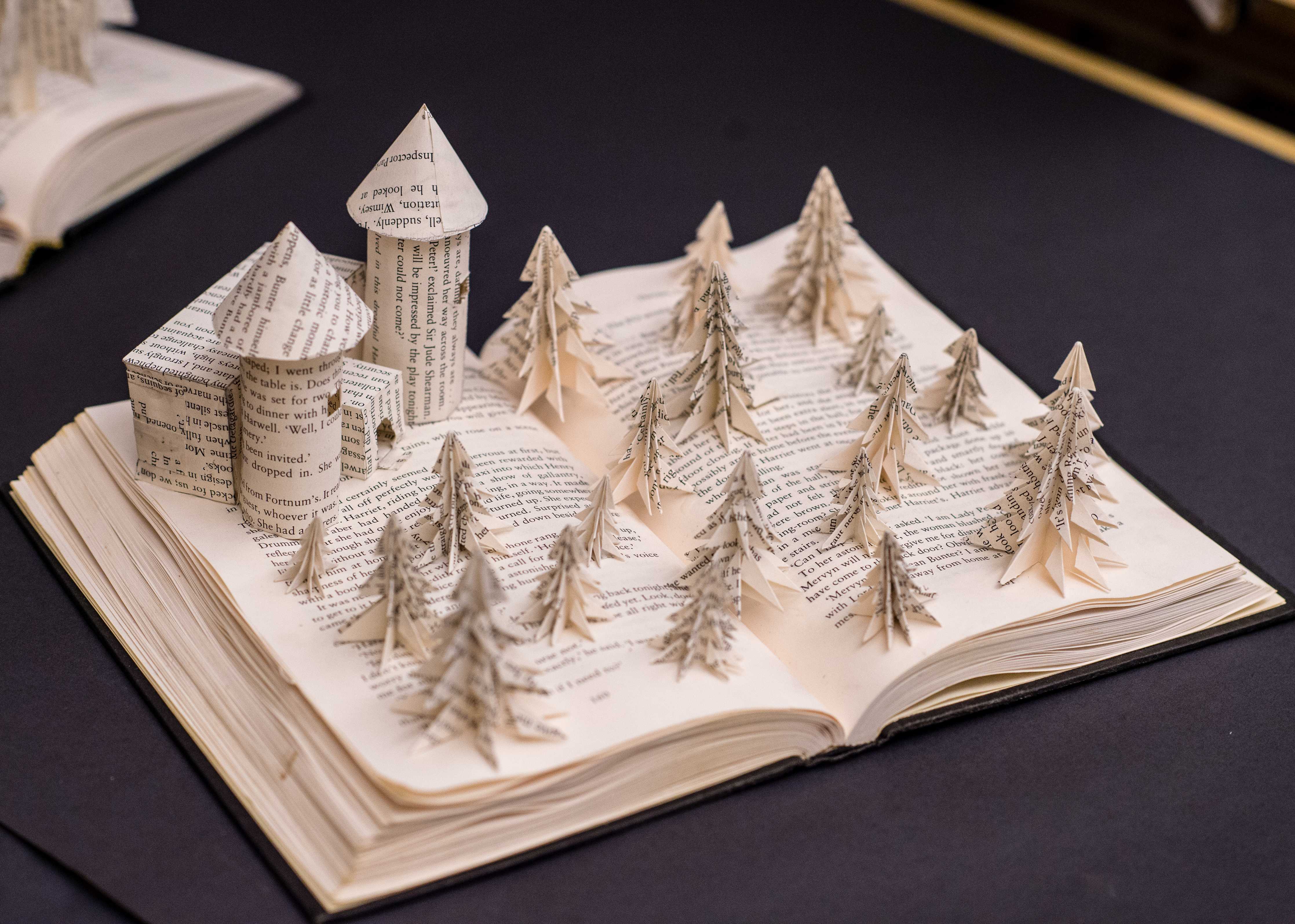 A paper sculpture of a castle and trees sits open on a book.