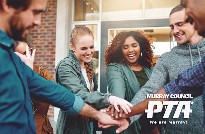 A diverse group of people with their hands stacked in a circle, smiling and looking united.
