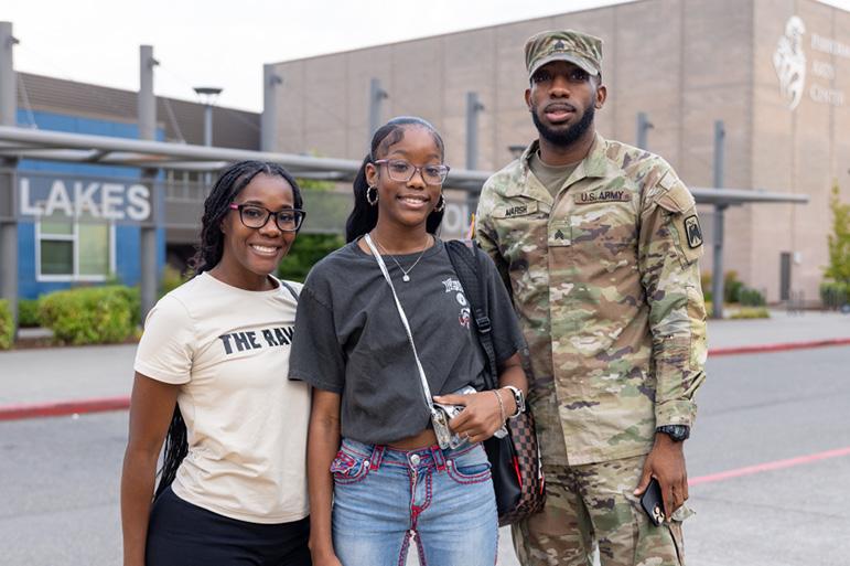 A soldier stands with family in front of a Lakes High School