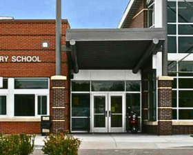 The entrance to an elementary school features a covered walkway and glass doors.