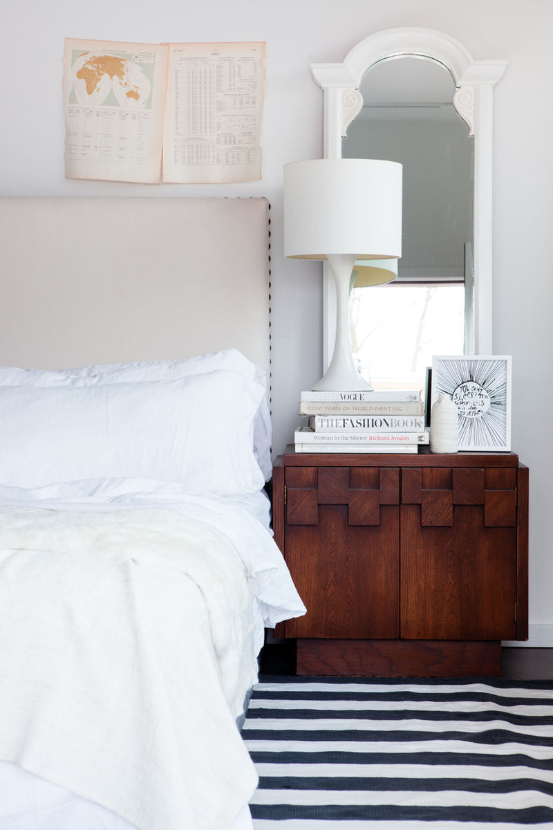 White on white bedroom with offbeat, rustic, retro, minimal modern design by Leanne Ford. Black and white stripe rug and sumptuous bedding create a hip vibe. #bedroomdecor #midcentury #boho #whitebedroom
