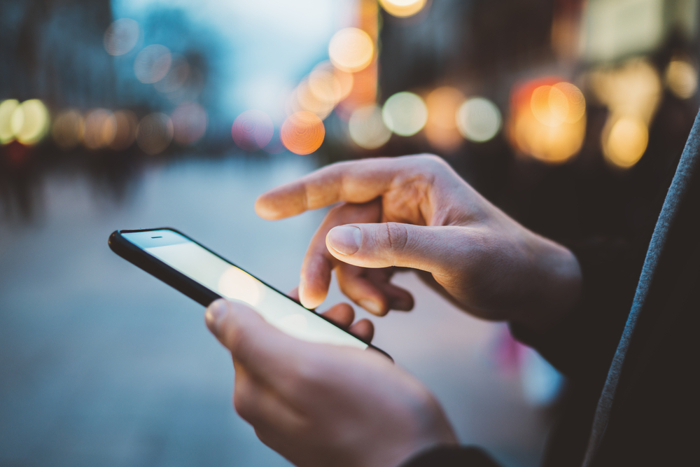 Man using mobile website on street at night