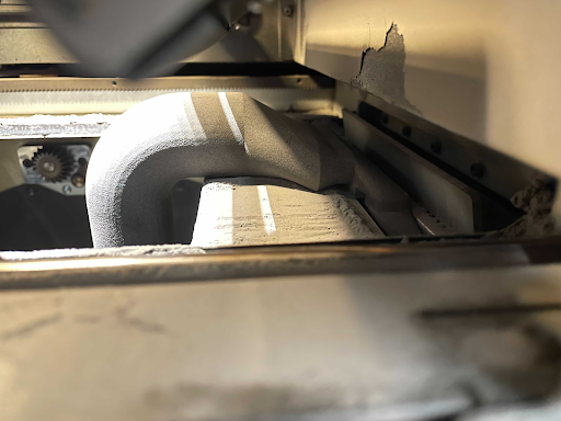 The vacuum attachment enters up through the print enclosre to hook into place and hold up the doser.