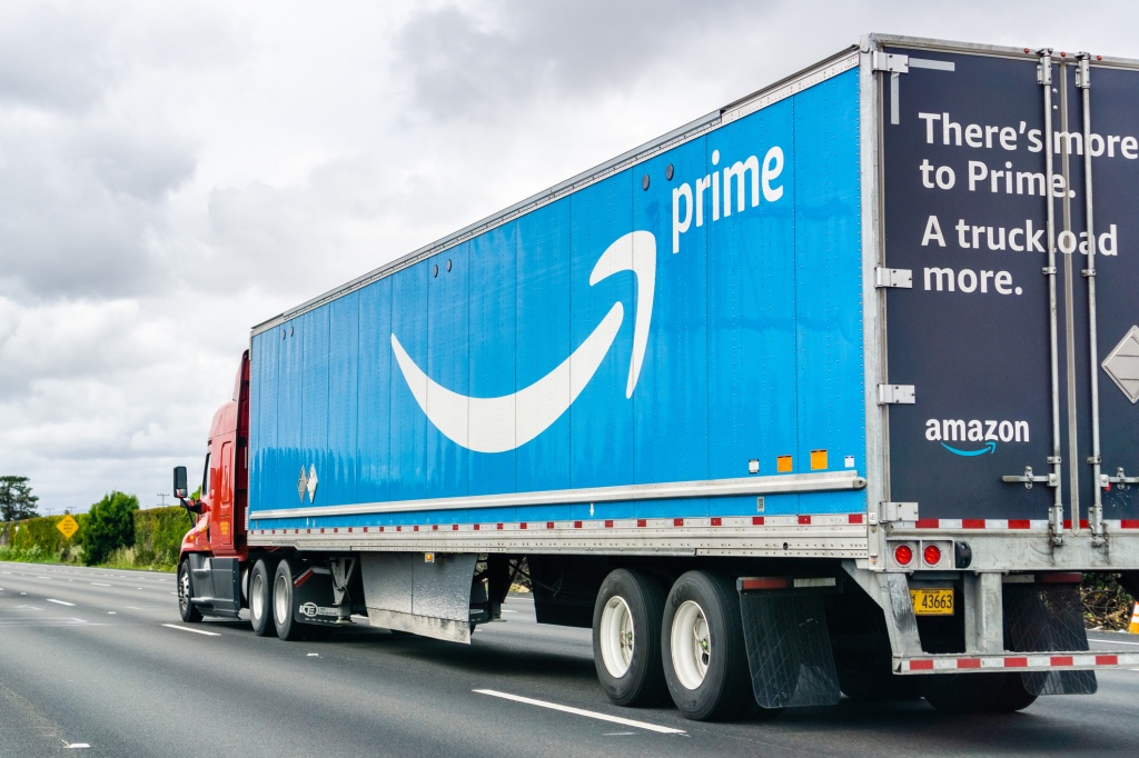 Amazon truck driving on the freeway, the large Prime logo printed on