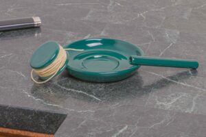 Ceramic ashtray sits on marble counter, round hempwick holder rests on it.