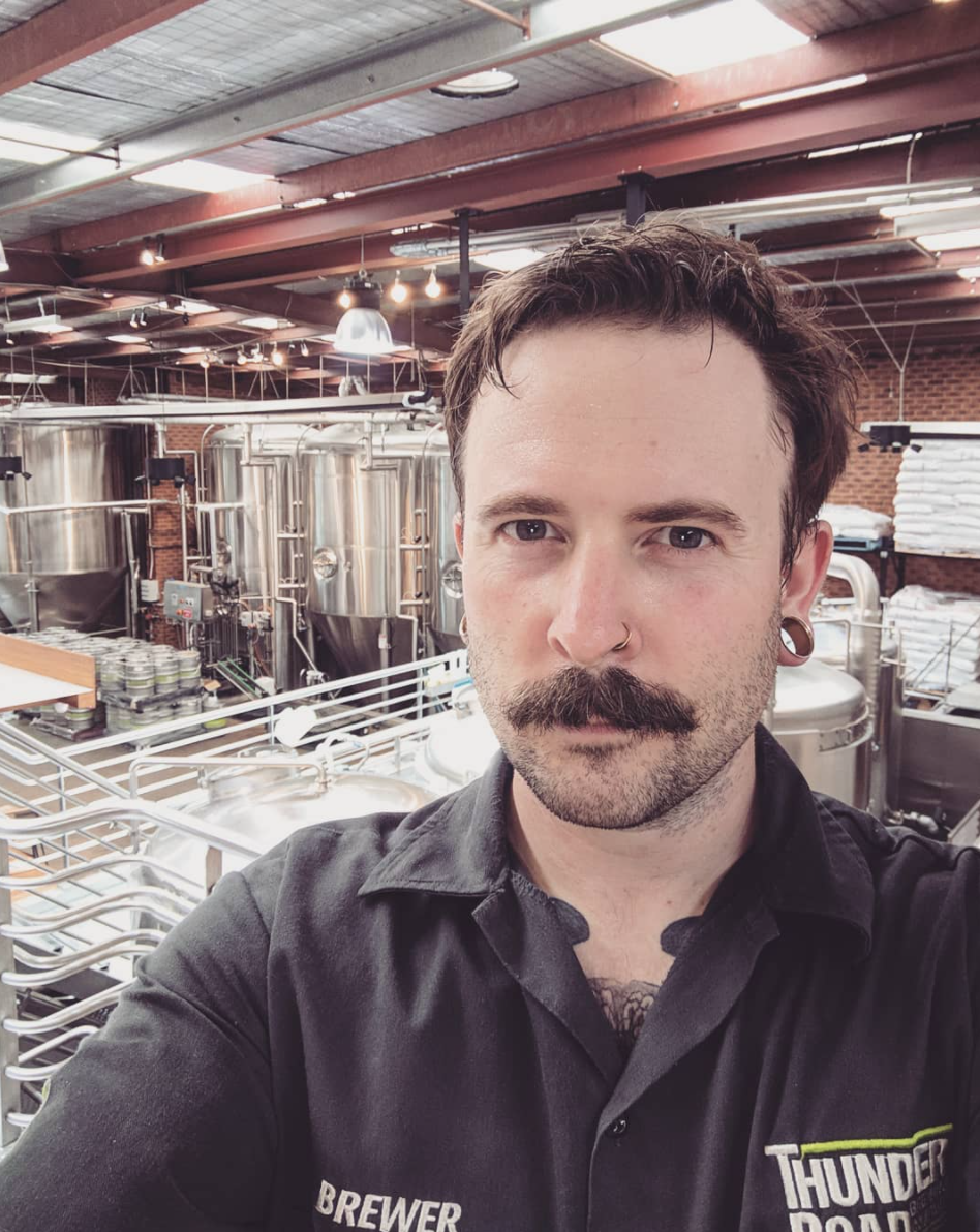 Photo of Murf Murphy in foreground, with brewery in the background.