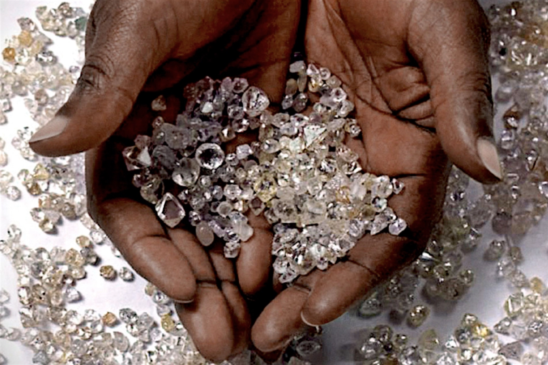 a miner holds many carats of cut diamonds in various colors