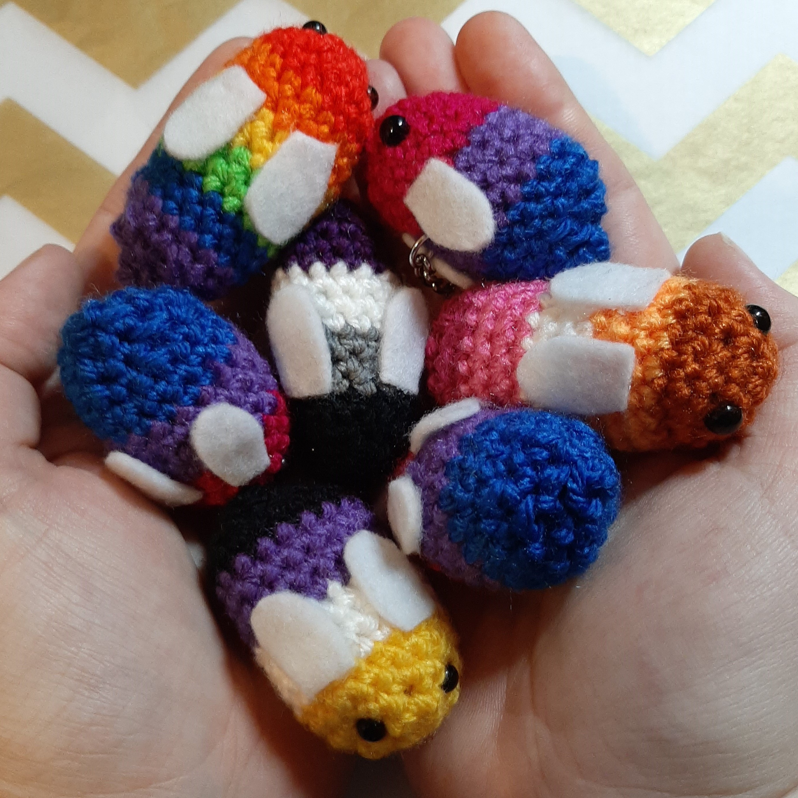 Crocheted bees in various pride flag colours