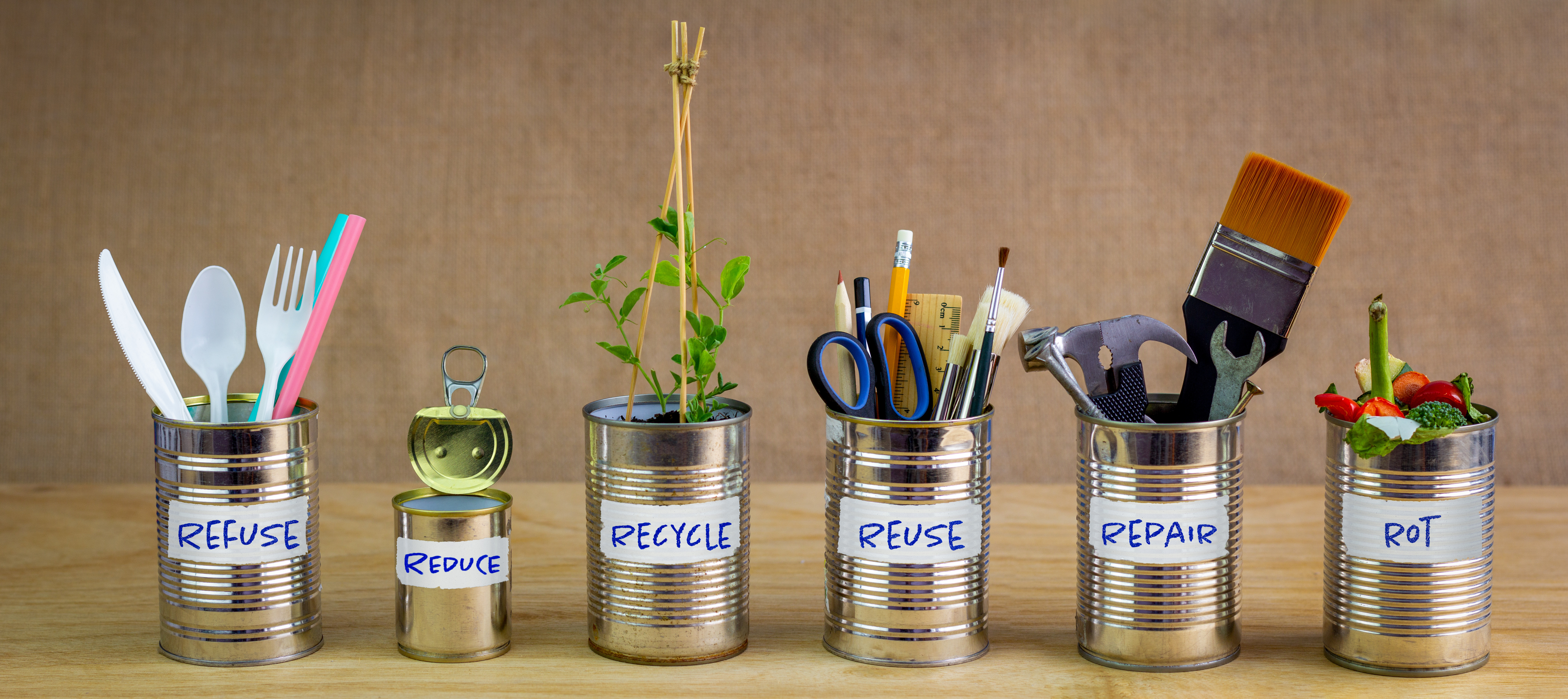 Five tin cans lined up in a row, each labelled with the one of the following: Reduce, reuse, refuse, recycle, repurpose