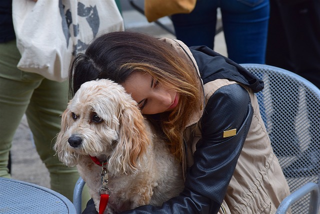 Woman huggin small white dog.
