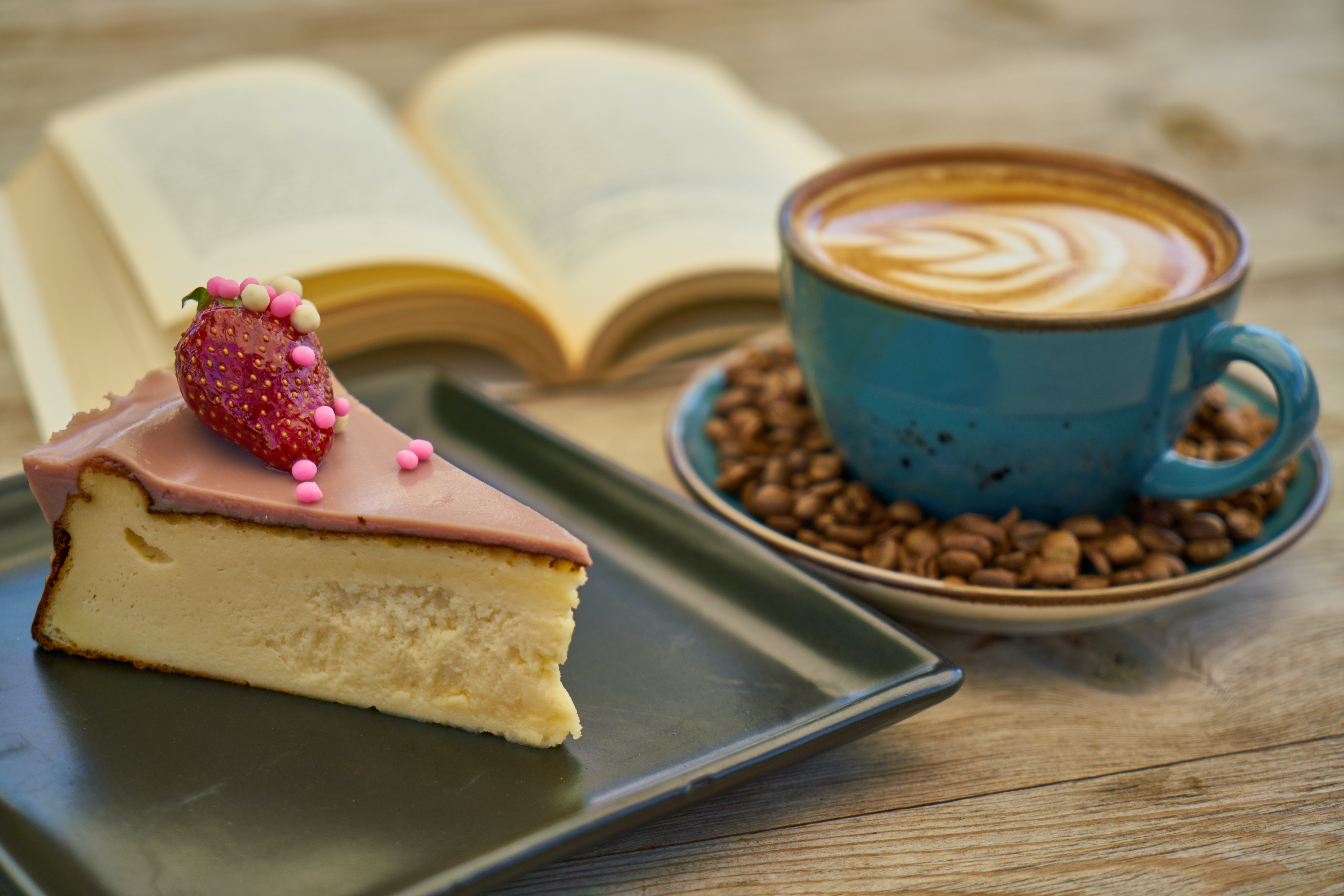 Cake, coffee and open book on a wooden table
