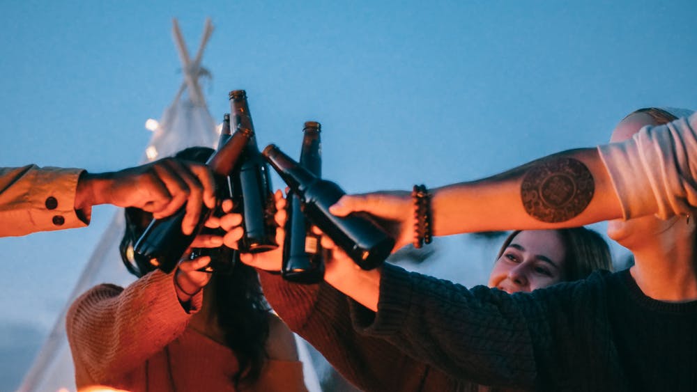 group raising a toast with bottles of beer