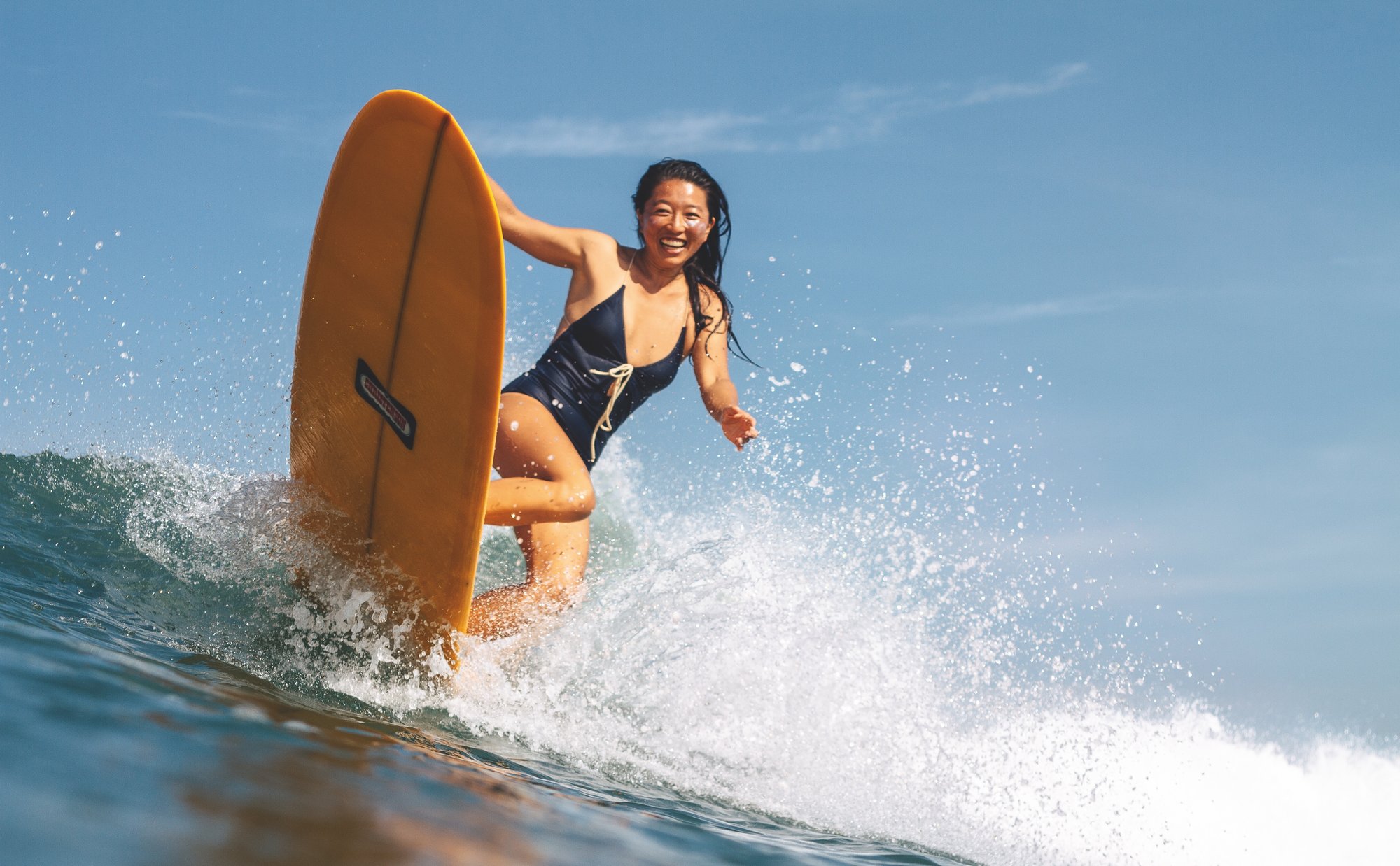 female surfing in sea with a yellow surfboard