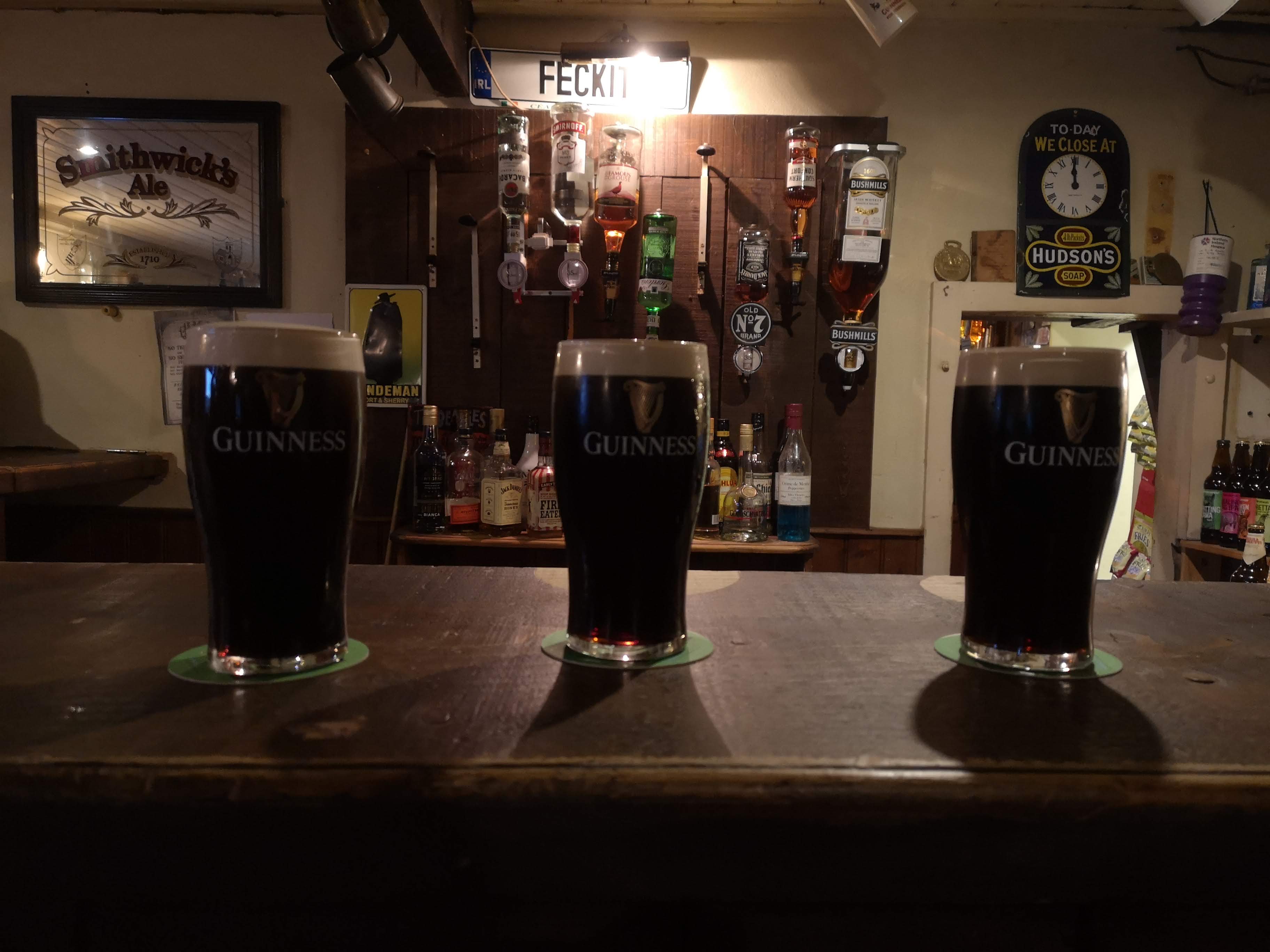 Three pints of Guinness on a bar