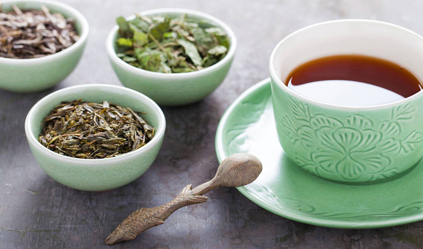 a trio of loose leaf teas accompanied by a brewed tea