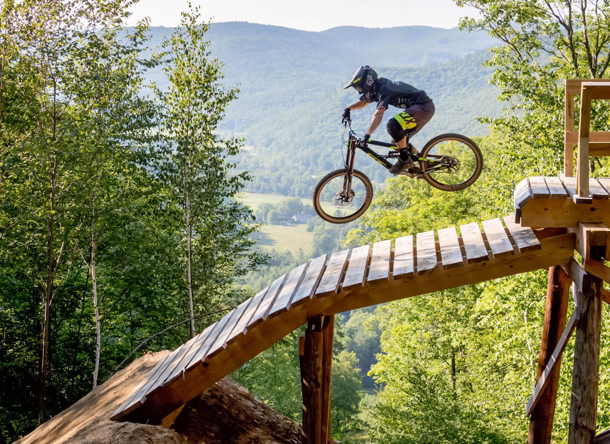 A man jumping a bike down a wooden ramp