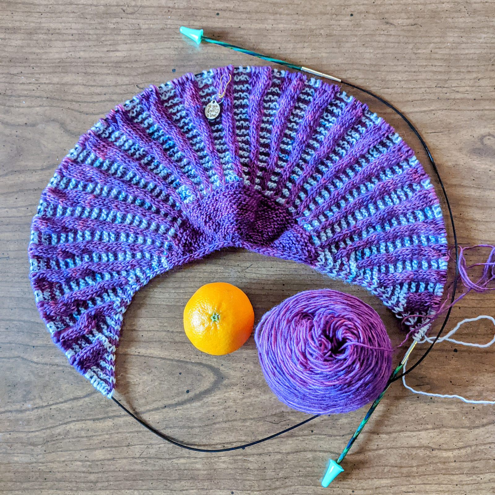 A picture of a hand knit item and a tangerine