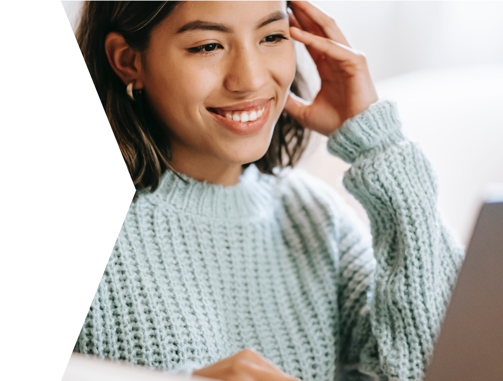 a young girl smiling at a laptop screen