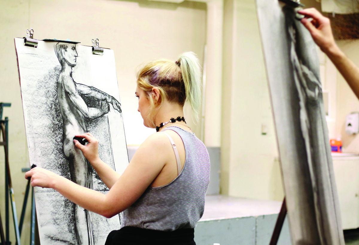 young blonde woman sketching a figure drawing of a man
