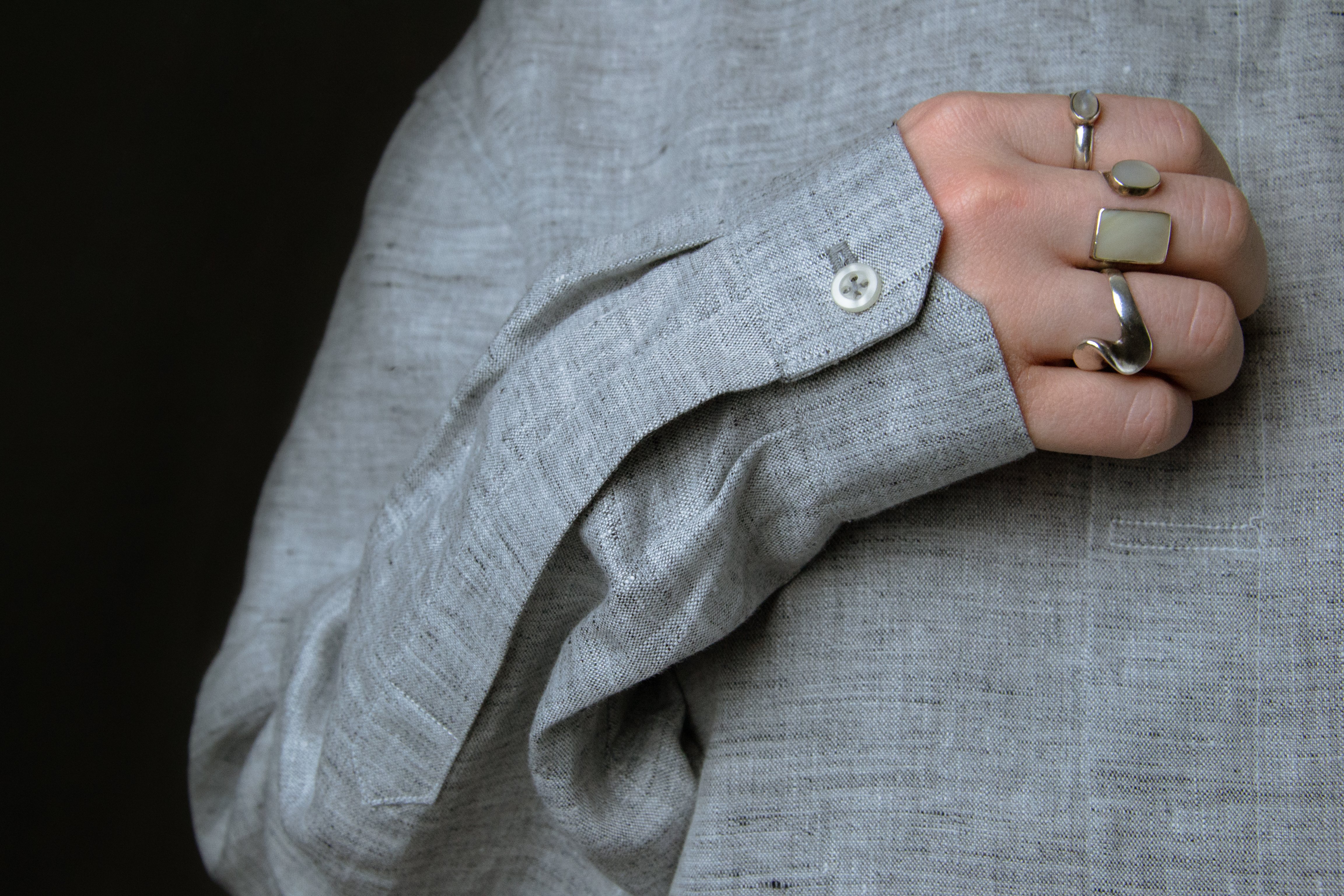 image detail of a linen shirt sleeve & hand with rings