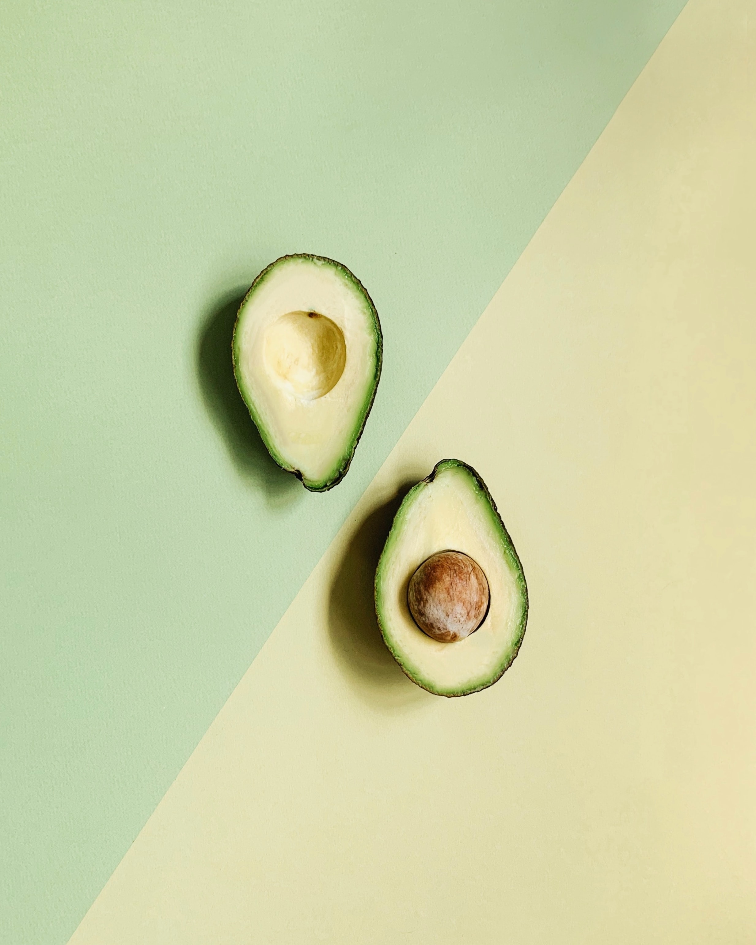 Image of open avocado with split yellow and green background