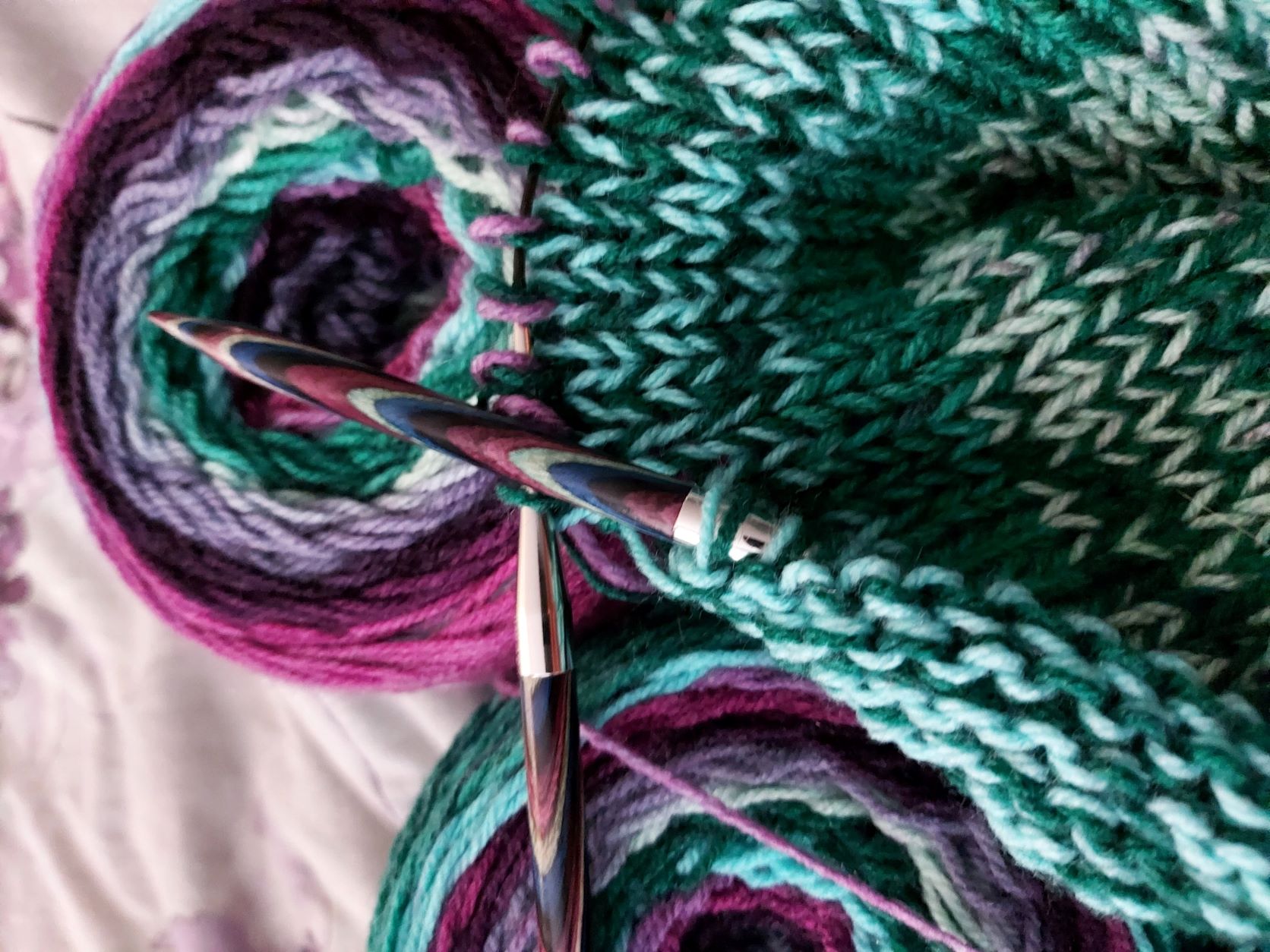 Purple and green yarn on purple and green knitting needles with a project in progress