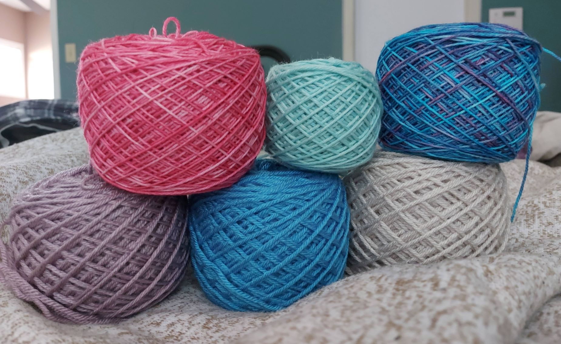 Six balls of yarn wound into cakes and stacked on top of each other