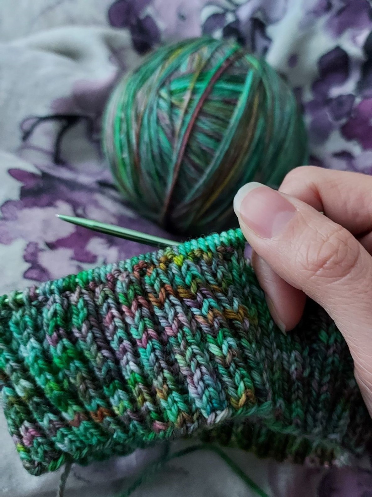 Green yarn with a brim of a hat knitted on knitting needles