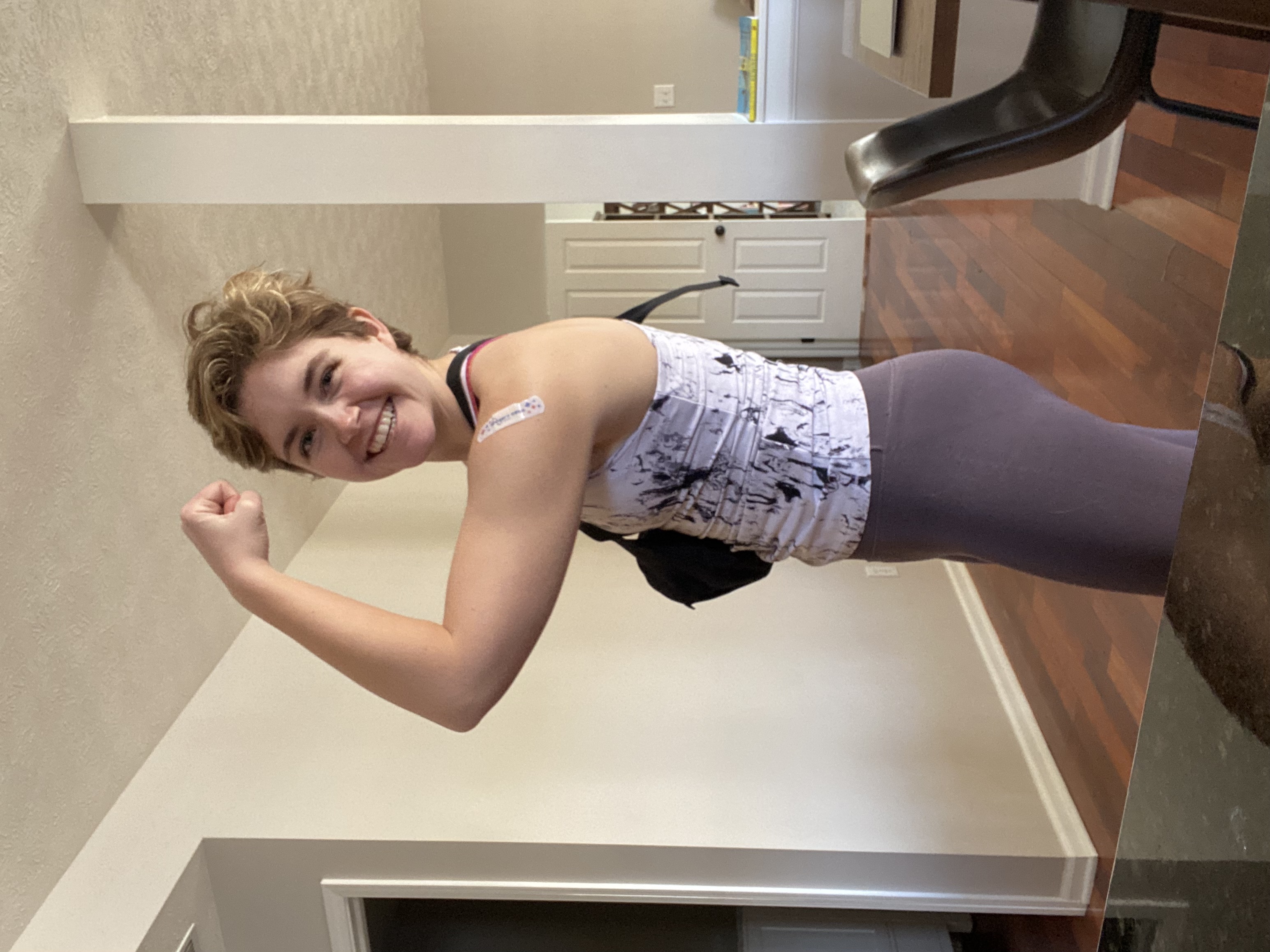 Morgan is flexing her right arm and looking at the camera smiling. She is dressed is atheltic gear like she recently worked out.