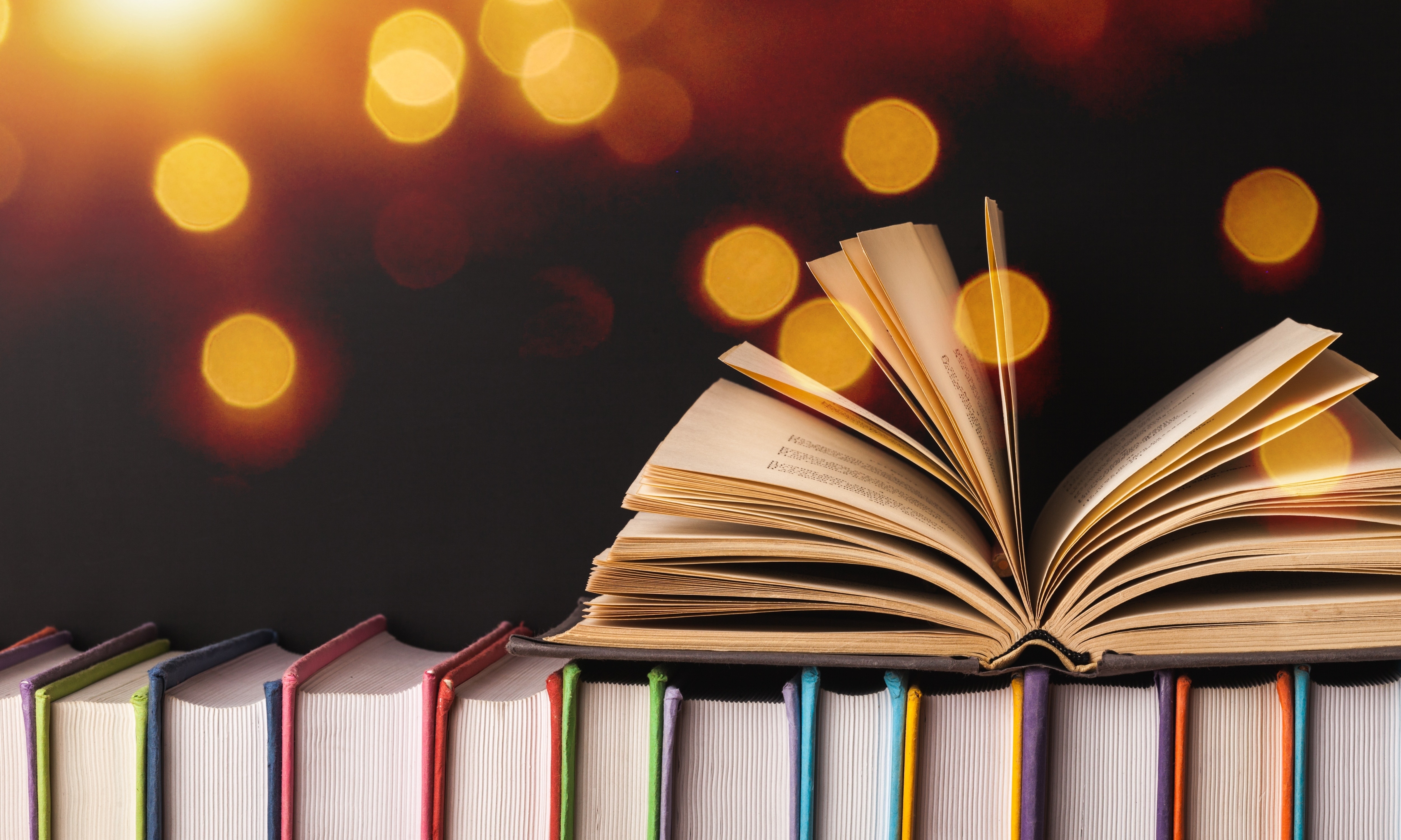 An open book lying on top of row of closed books