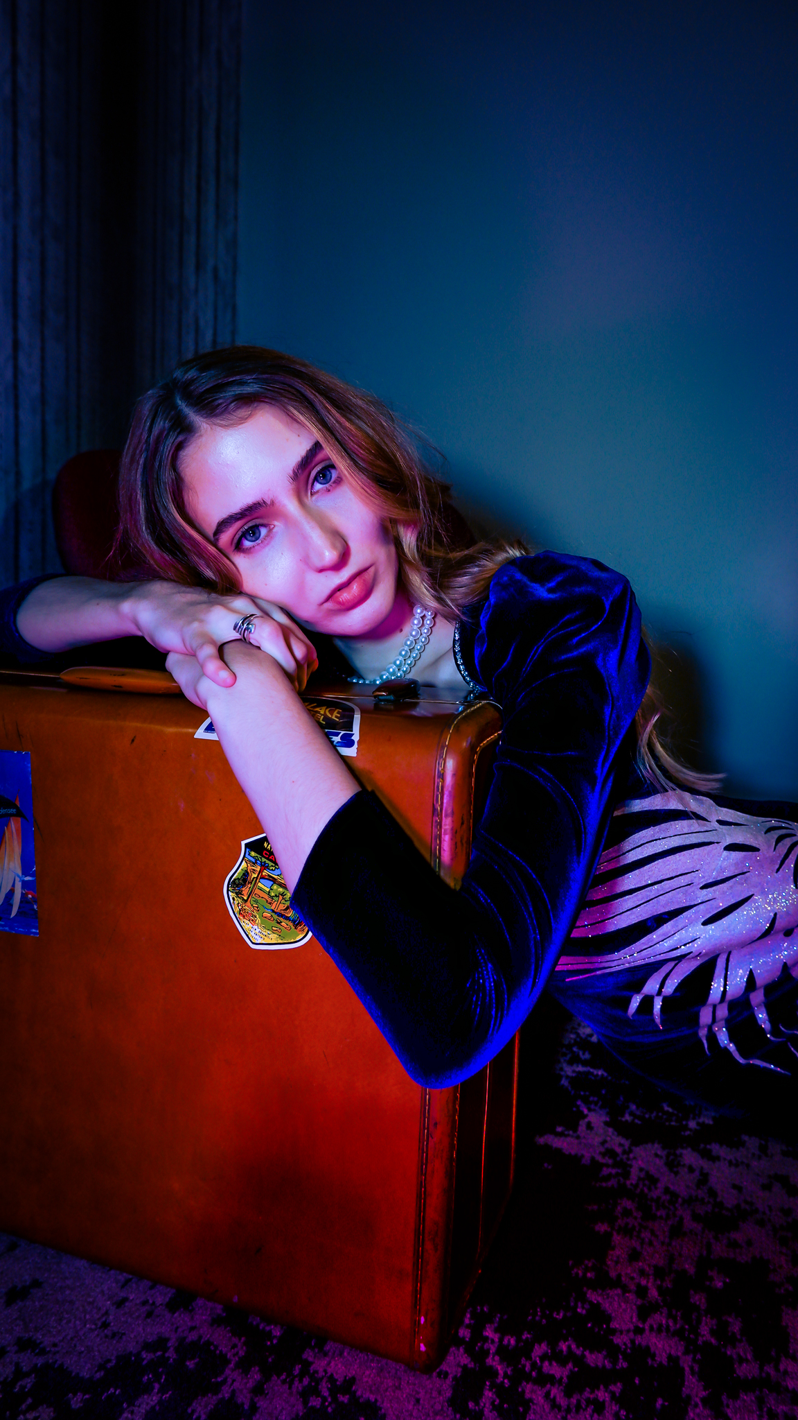 Photograph of woman with a suitcase, blue tones cover the photo