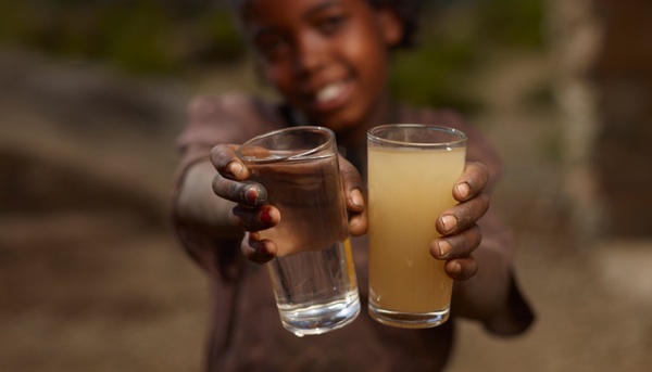 young girl holding glass of clean and dirty water
