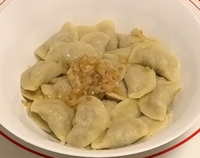 Ukrainian Varenyky are in a plate sprinkled with fried onion with butter