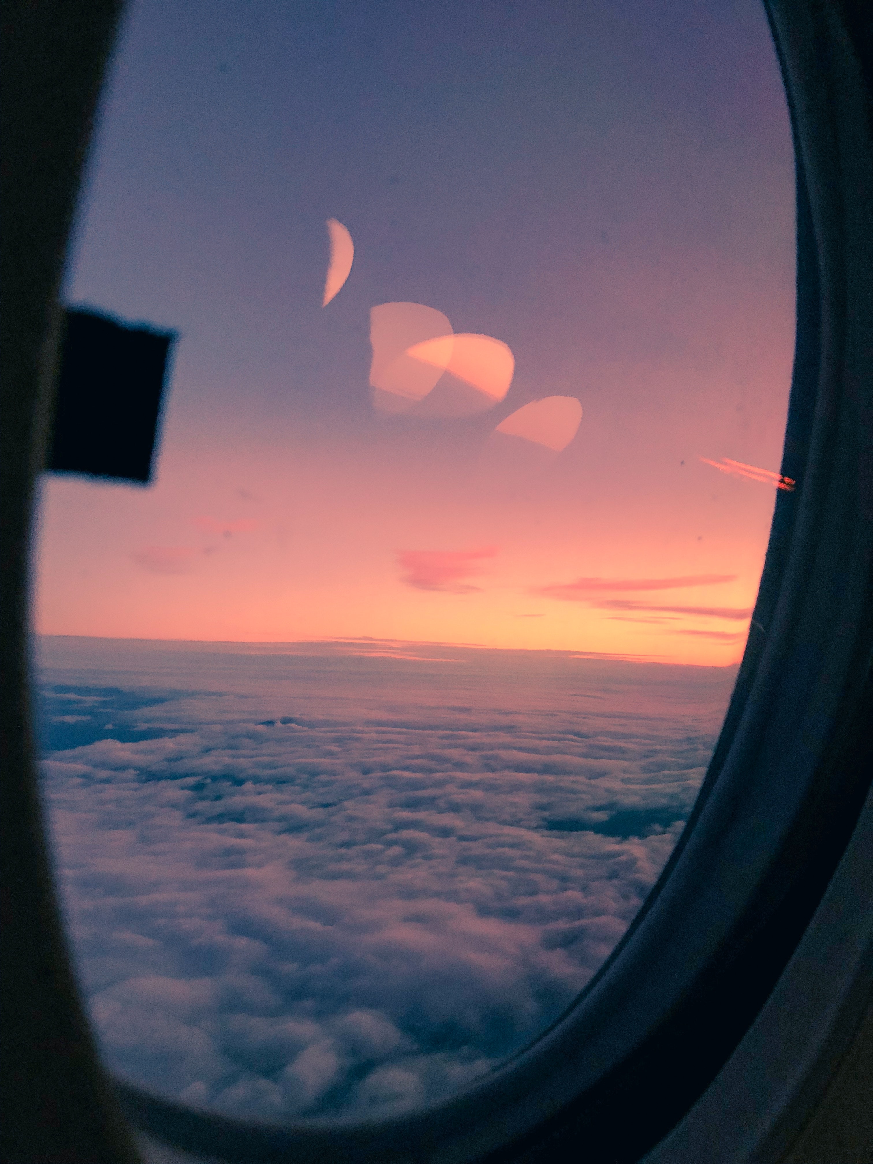 plane window looking over clouds and sunset