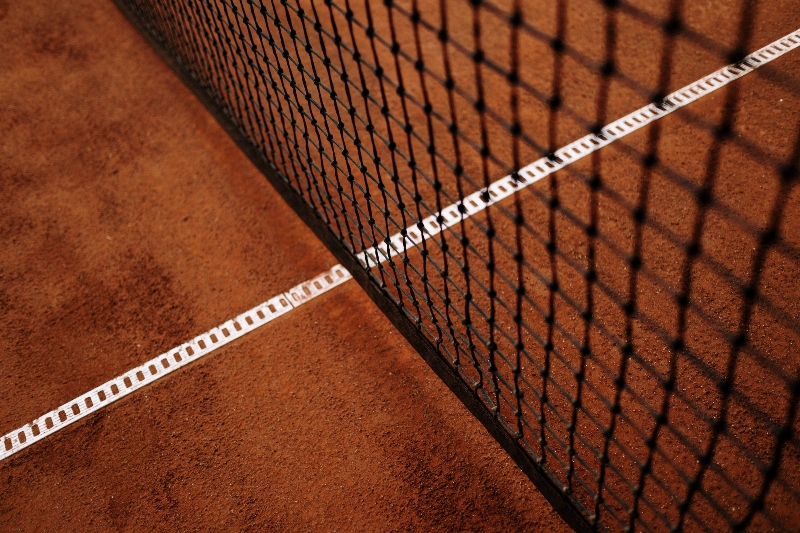 A close up of the tennis net on clay court surface