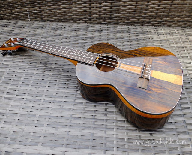 a tenor ukulele on top of a raffia material